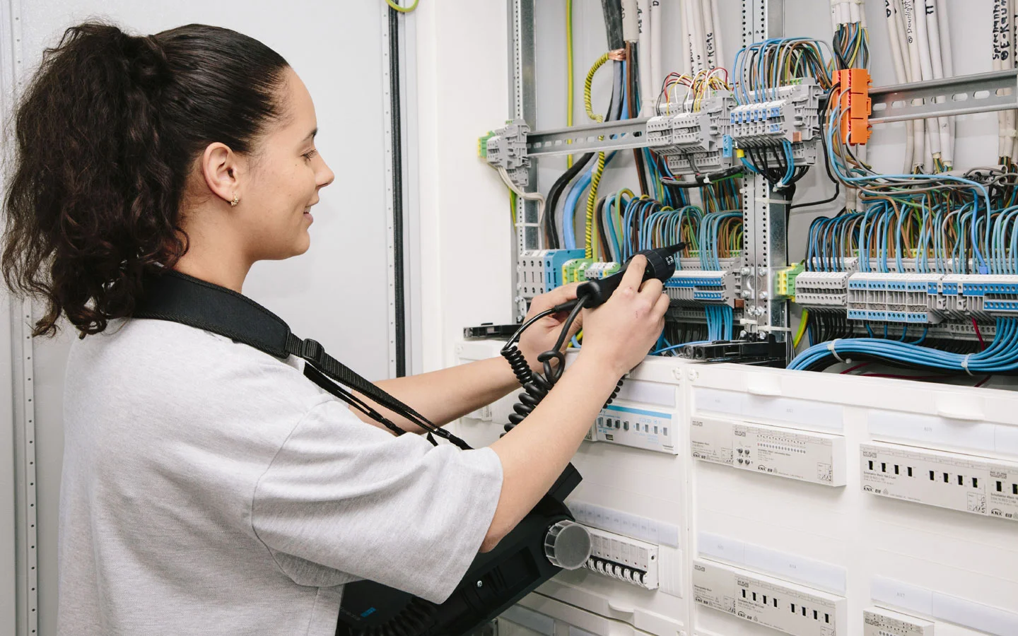 E-CHECK - Mitarbeiterin prüft im Schaltschrank mit einem Meßgerät &middot; Elektro Roth